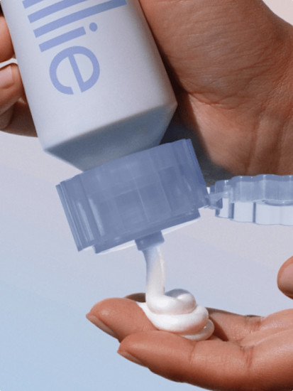Woman squeezing a bottle of Ultra Gentle Billie Whipped Shave Cream into her hand