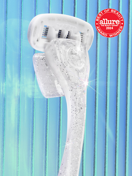 Clear electric toothbrush with sparkly handle against blue striped background, featuring Allure Best of Beauty 2024 award badge.