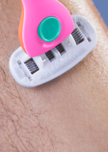pink, orange, and teal razor being used on a leg