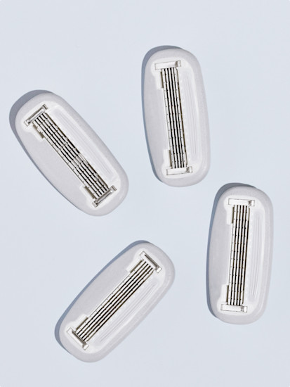Four Billie razor refill blades on a grey periwinkle background