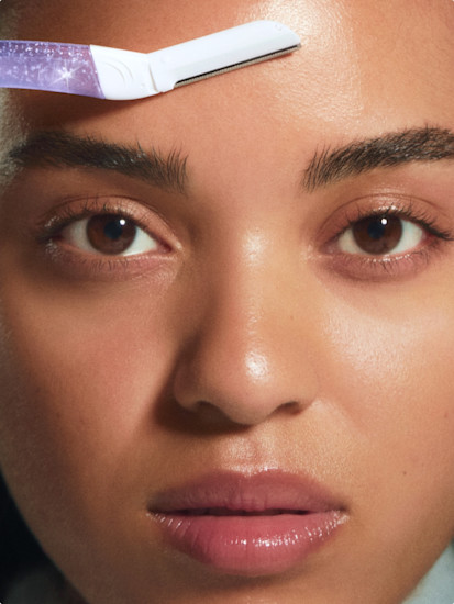 Woman using purple sparkle Billie dermaplane tool on her forehead