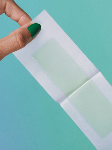 hand peeling open a face wax strip