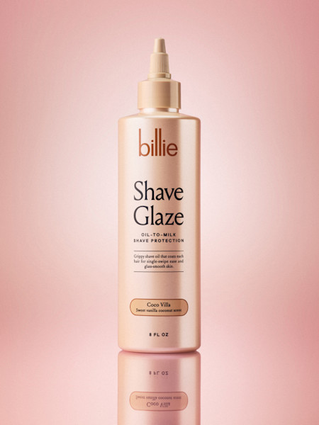 Bottle of Billie Shave Glaze oil-to-milk shave protection in Coco Villa scent against a pink background.