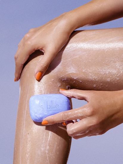 Woman using Billie Body Buffer bar to exfoliate her leg