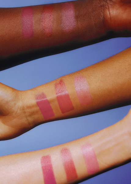 Three shades of pink tinted lip balm swatched on dark, medium, and light skin tones 