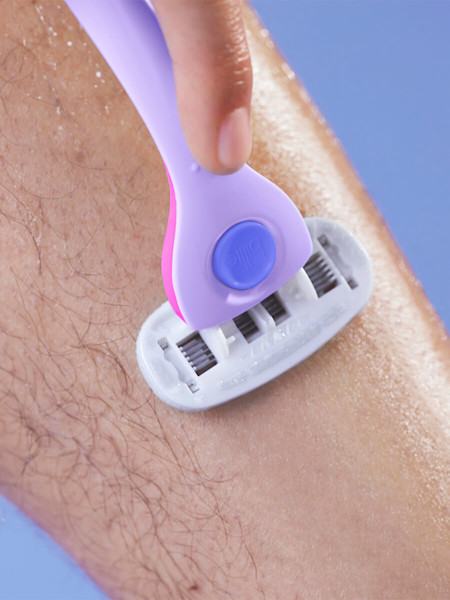 hand shaving shin with the billie razor in purple and pink