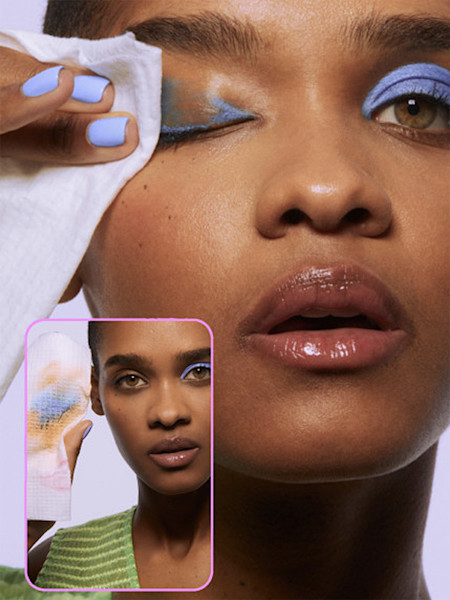 Person removing blue eyeshadow with wonder wipe make up remover wipe, wearing matching blue nail polish, with smaller inset image.