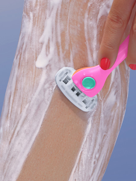 model shaving leg with whipped shave cream and pink and teal razor